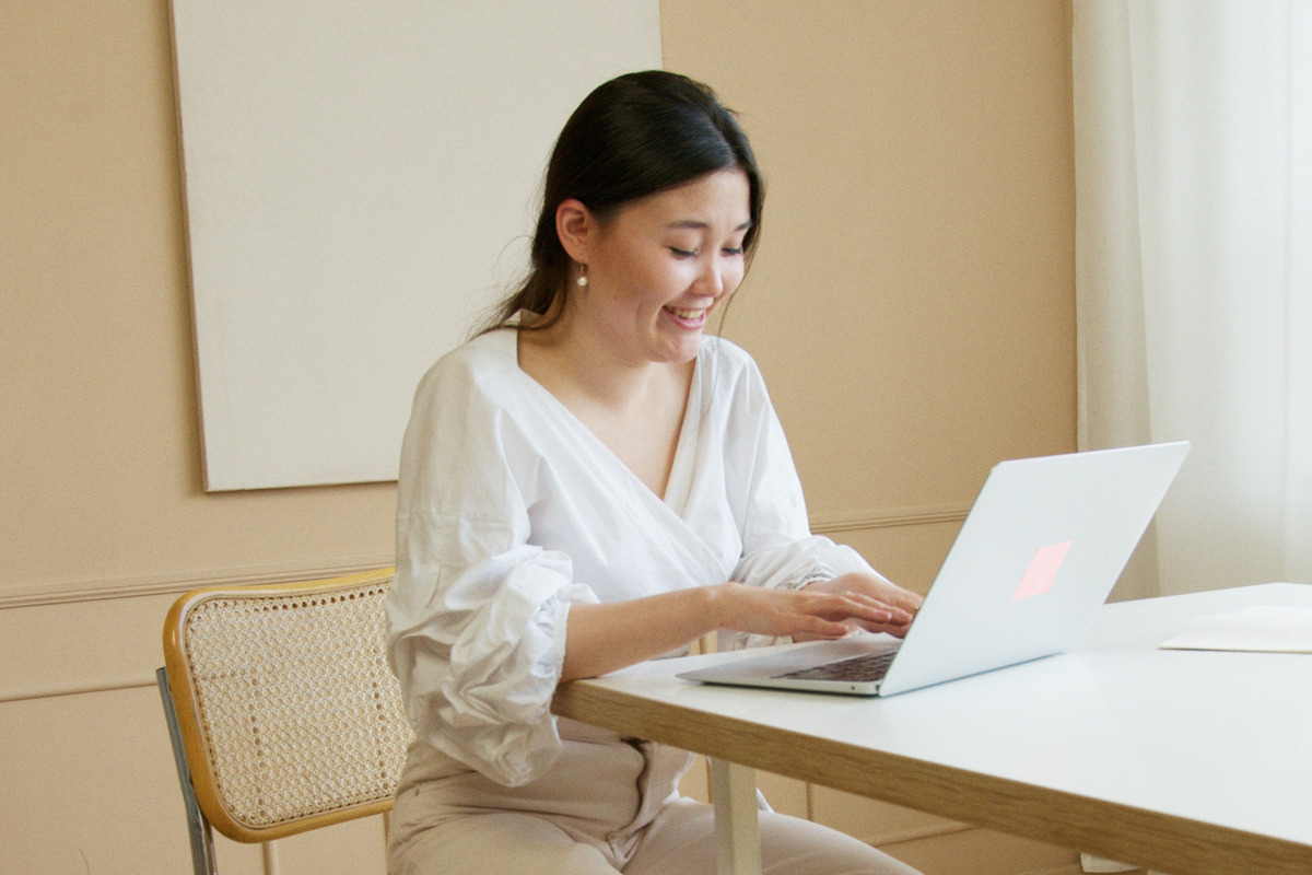 Lady sitting at a table typing on a laptop